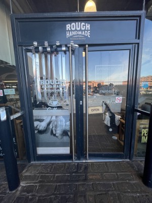 Glass double door with grey frame and handle in centre. Push to open.