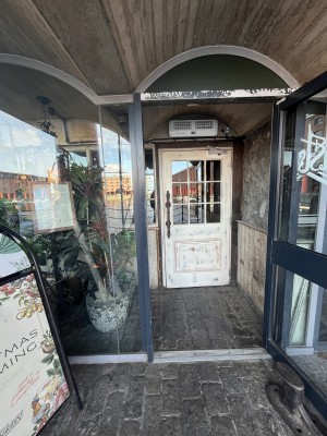 Glass door with a grey frame and a metal handle on left. Pull to open.