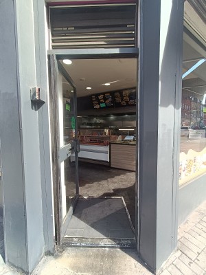Glass door with black, metal frame. Push from black handle on right to open.