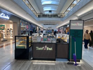 From mall corridor facing straight. Food display counter to left. Paying till ahead.