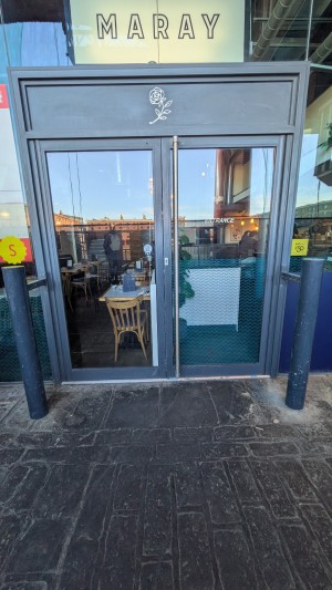 Glass doors with grey frame. Pull handle in center to open.