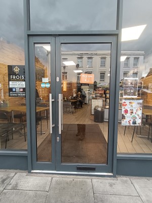 Glass door with black, metal frame. Push silver handle on left to open.