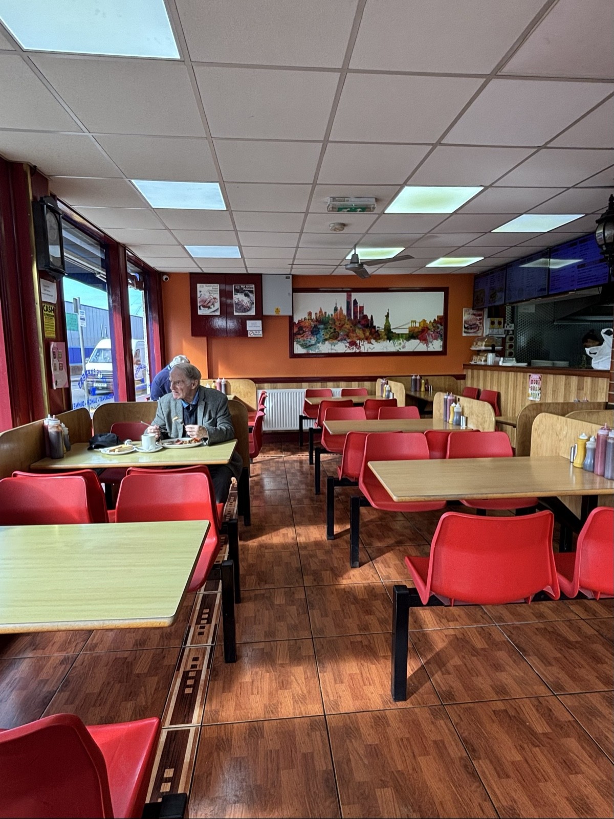 From entrance facing left, tables and chairs along glass wall to the left, tables and chairs to the right