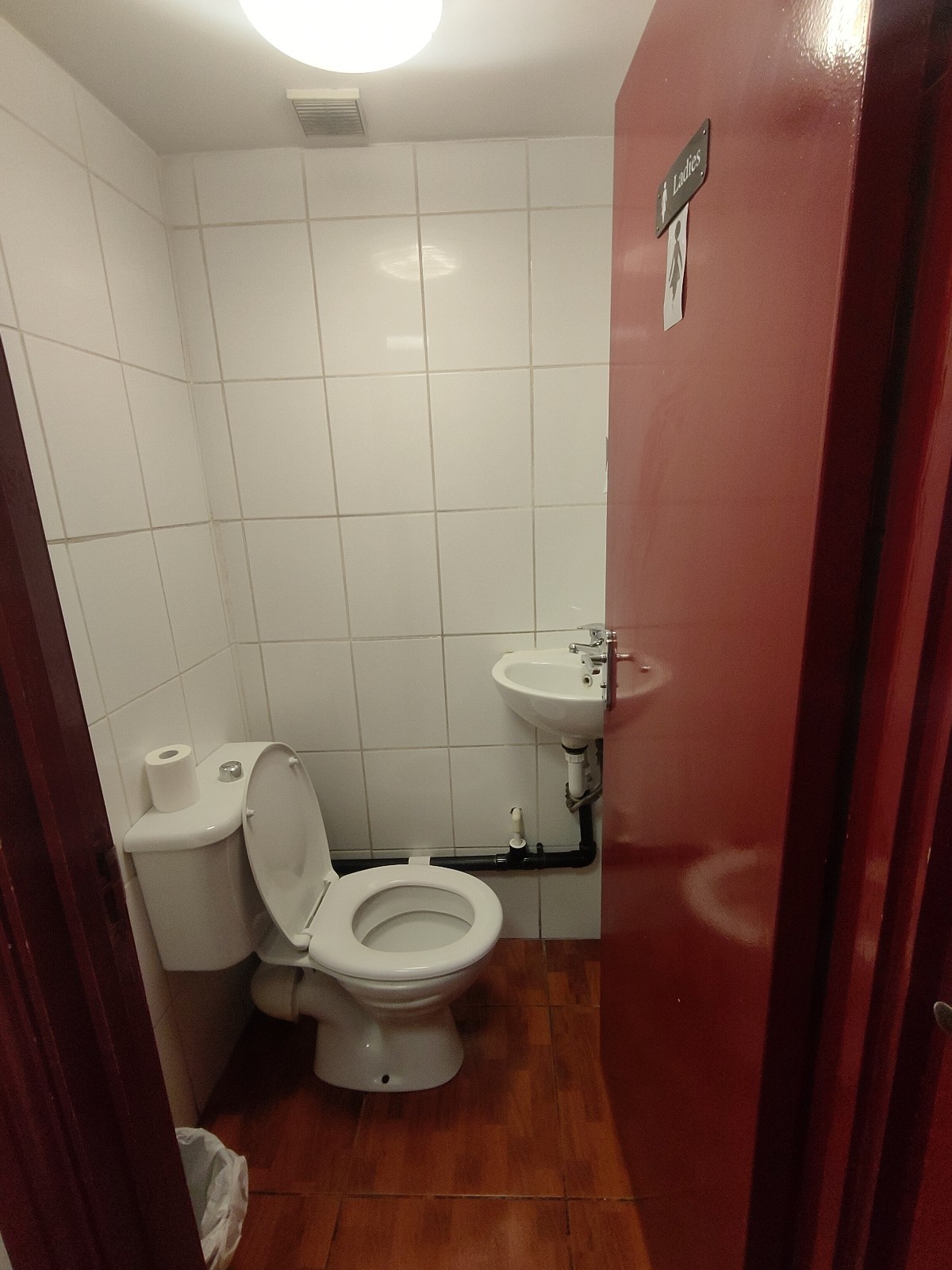 From doorway, facing straight. Toilet on left. Sink at back right.
