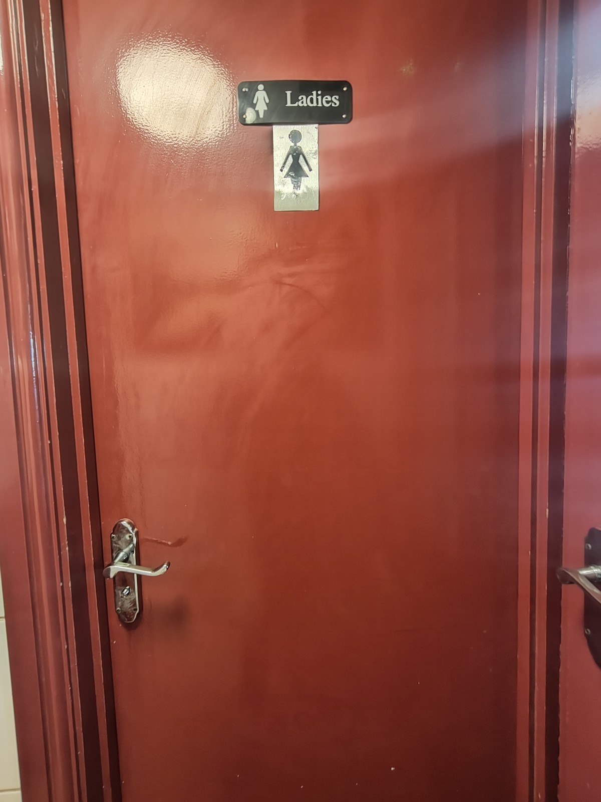 From doorway, facing right. Brown, wooden door ahead. Push from silver handle on left to open.