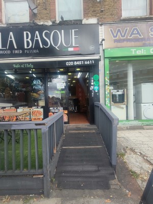 From sidewalk facing venue. Built in ramp ahead. Fenced half wall on both sides.