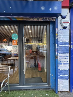 Glass door with black frame and metal handle on the left. Glass wall to the left