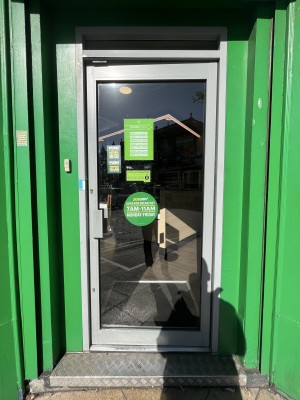Glass door with a grey frame. Handle on left side. Push to open.