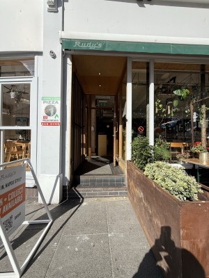 From street facing venue. 2 steps up to entrance. Wooden glass door. Metal handle on left. Pull to open.