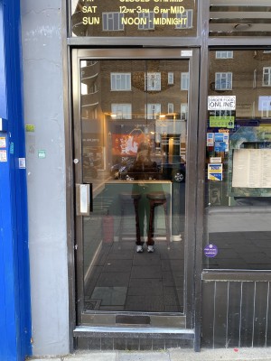 Black framed glass door. Black metal handle on left side of door. Push from left to open.