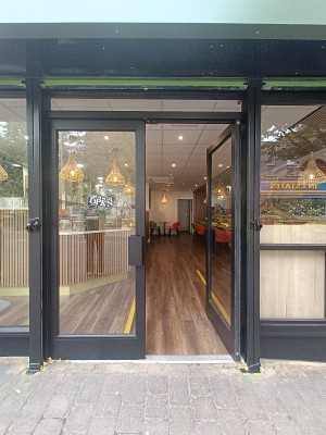 Glass doors with black, metal frame. Push from middle to open.