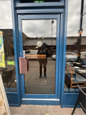 Glass door with a blue frame and brown handle on left. Push to open.