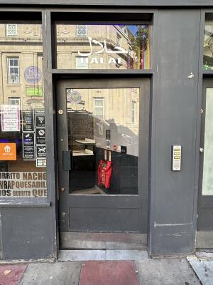 Black door with glass window, door handle to the left, push to open.