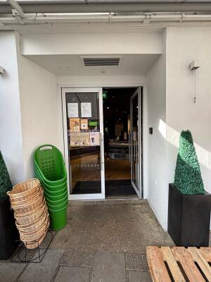 Open archway ahead with planters on both sides. Glass doors with white frame on back. Push via handle in centre to open.