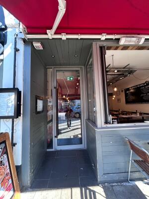 From sidewalk facing straight. Archway towards door ahead.