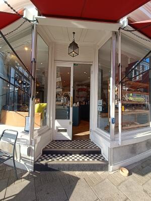 From street, facing venue. Two steps up to glass doors with white, wooden frames. Push from middle to open.