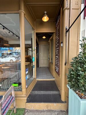 Open archway ahead to glass doors with beige frame on back. Push door from left to open.