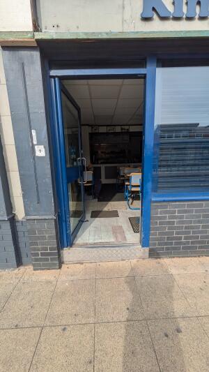 Glass door with blue frame. Push metal handle on right to open.