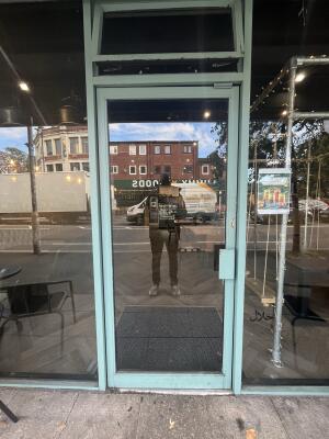 Glass door with a green frame. Handle on right. Push to open.