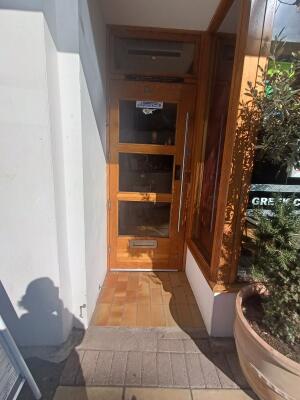 Glass door with brown, wooden frame. Pull silver handle on right to open.