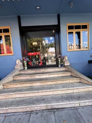 From sidewalk facing venue. Flight of concrete stairs towards door ahead.