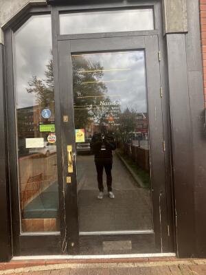 Glass door with a brown frame and handle on left. Pull to open.