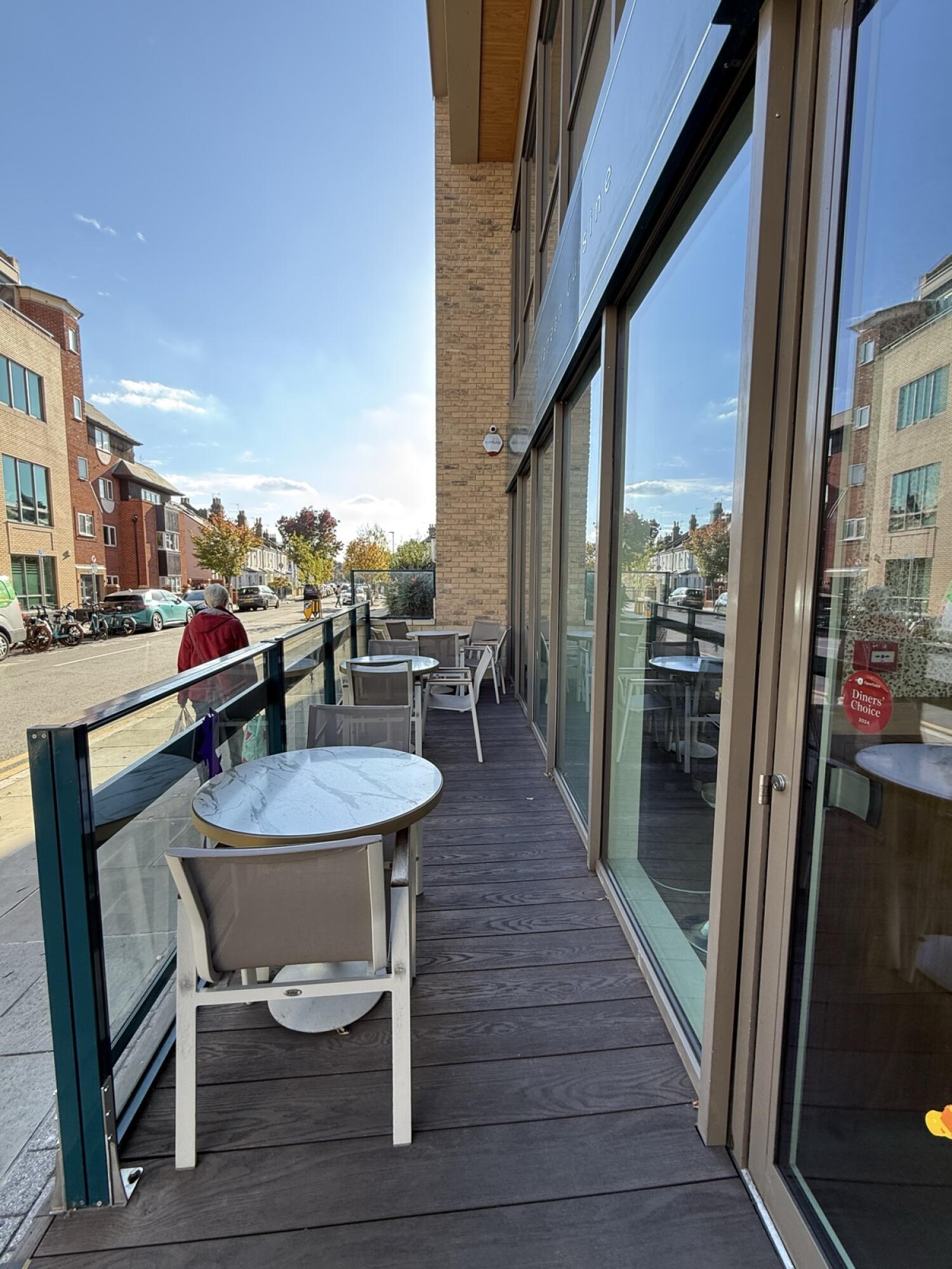 From door facing right. Tables and chairs along left side, fence behind. Step to street on left.