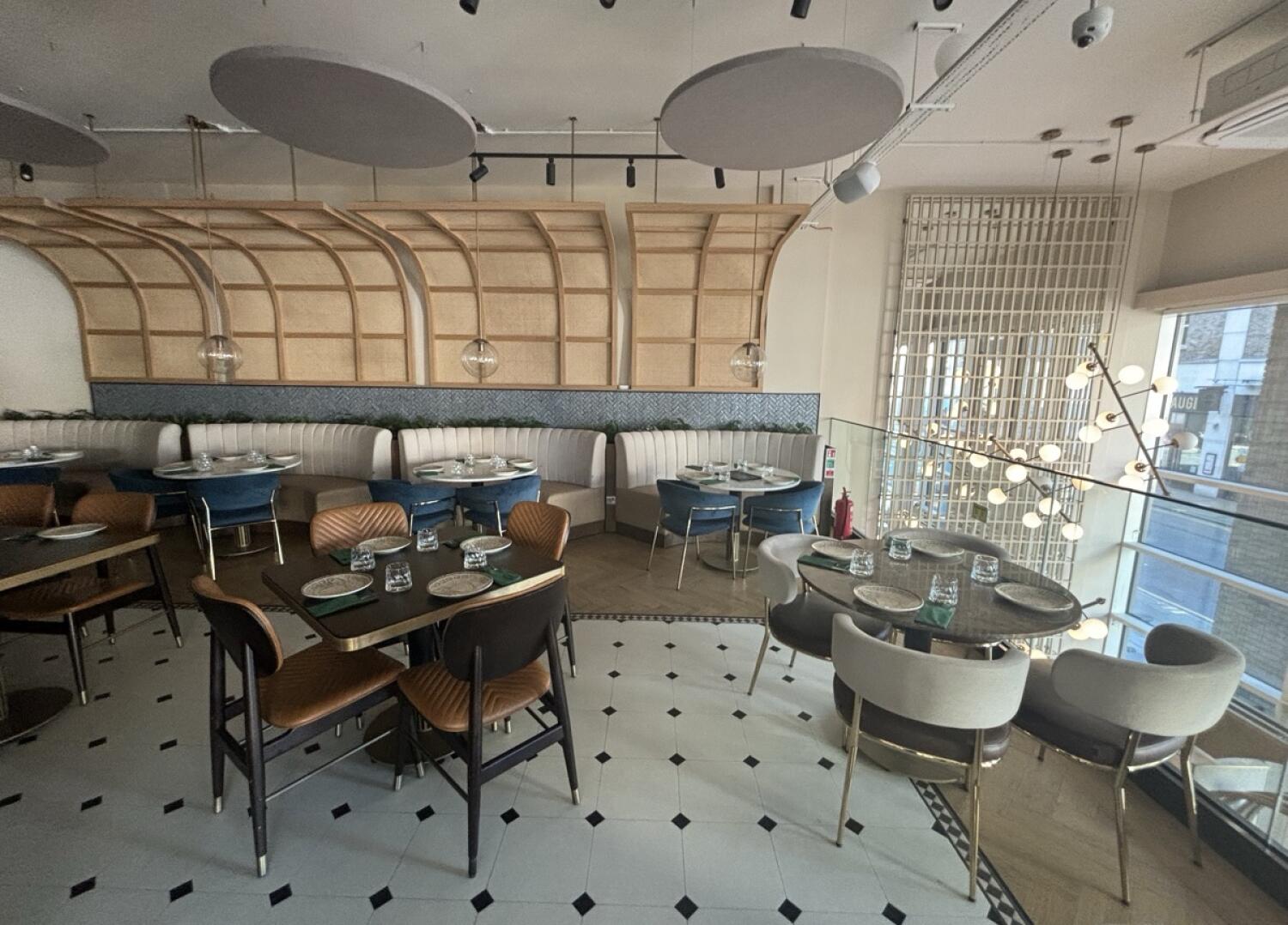 From archway facing straight. Tables and chairs ahead. Half booths behind along back wall.
