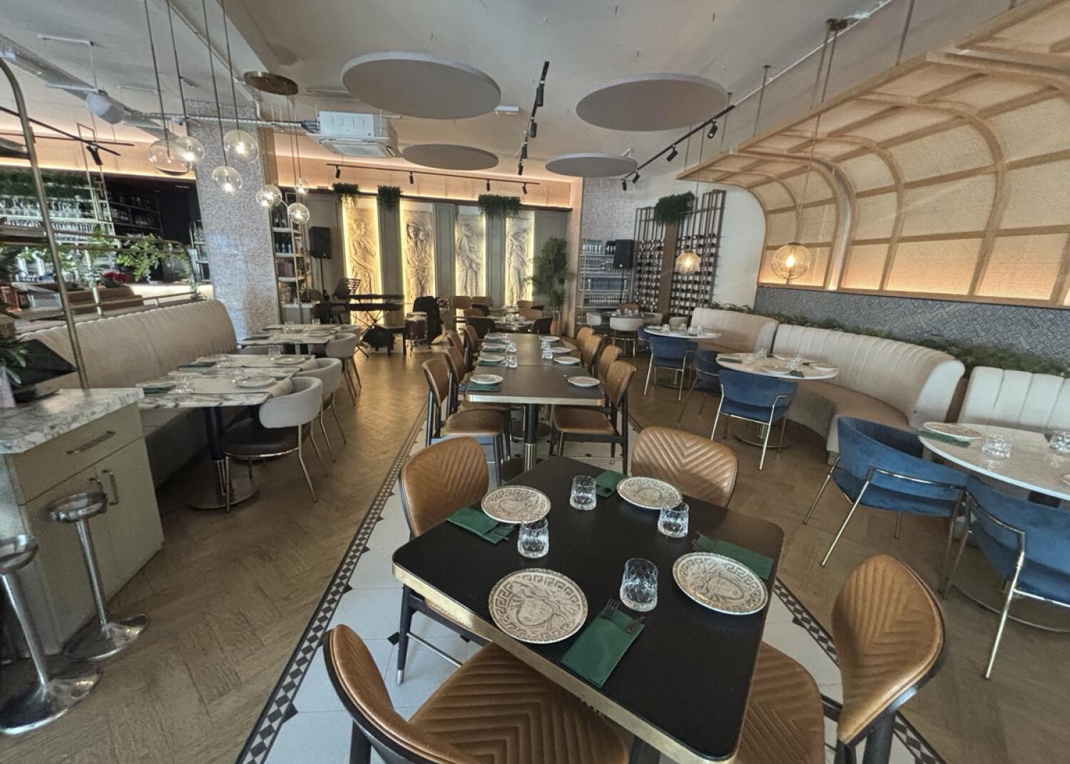 From archway facing left. Tables and chairs ahead and along back. Half booths along left and right wall.
