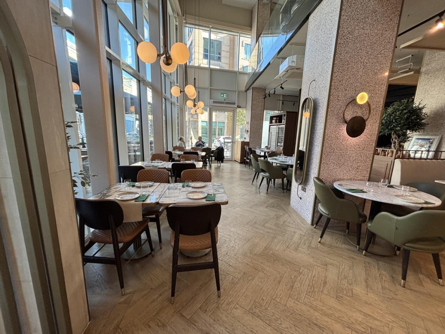 From entrance facing left. Tables and chairs ahead, along left wall. Table on right, followed by column.
