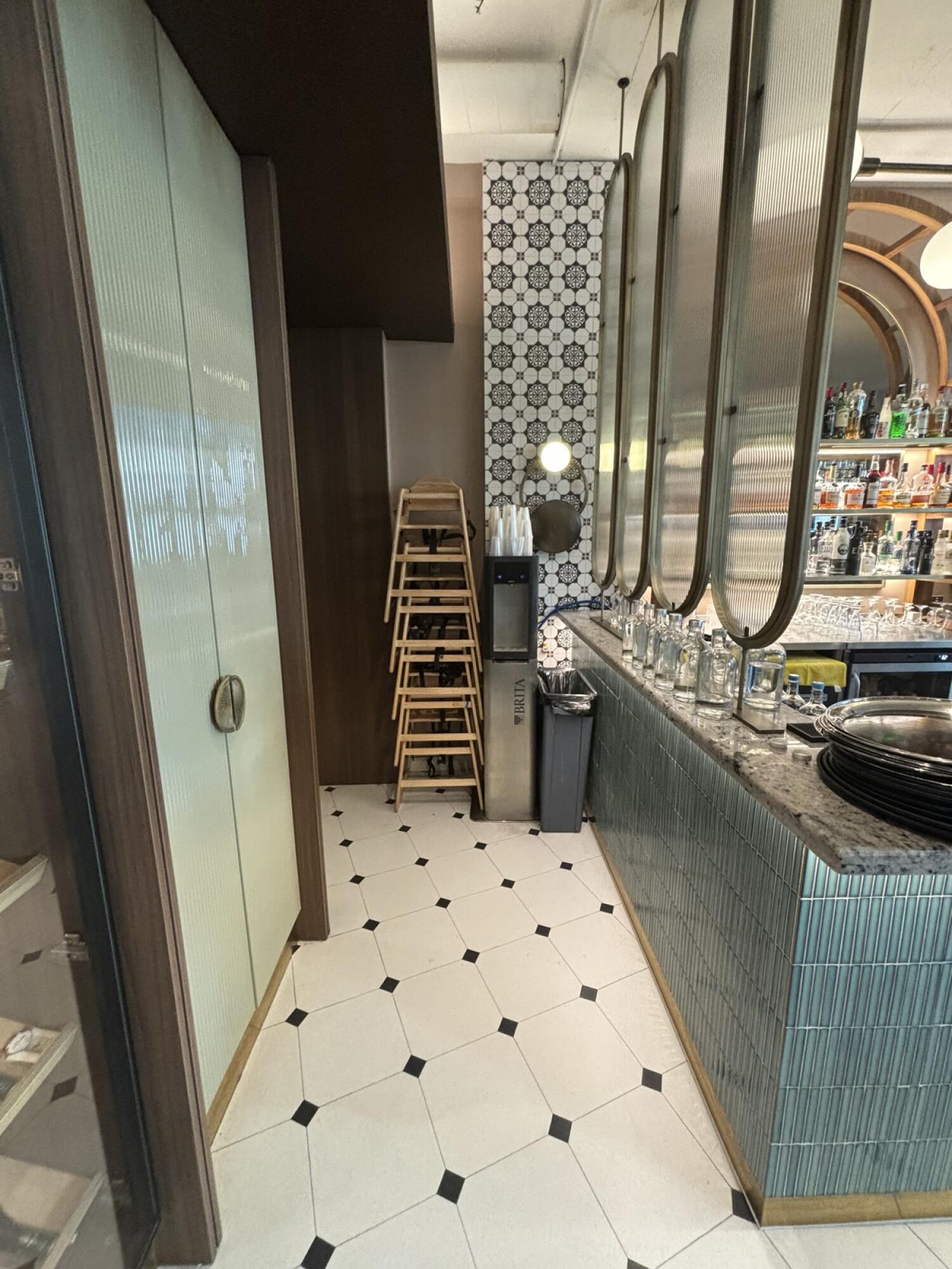 From end of counter facing right. Bar along right. Baby high chairs at back. Shelving on left.