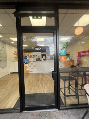 Glass door with black frame and metal handle on right. Push to open.