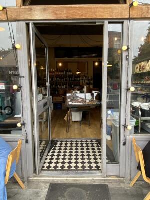 Grey framed glass door. Grey metal handle on right side of door. Push from right to open.