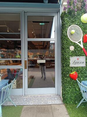Glass door with grey, wooden frame ahead. Push from left to open.
