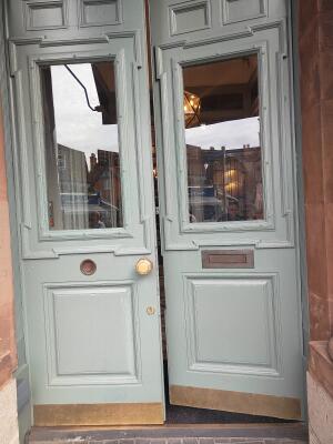Glass door with green, wooden frames ahead. Push from middle to open.