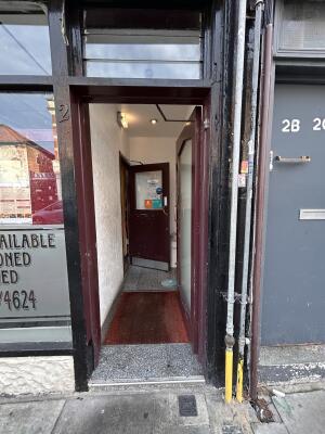 Preceding glass door with red wooden frame. Push metal handle from left to open. Path towards second door in center.