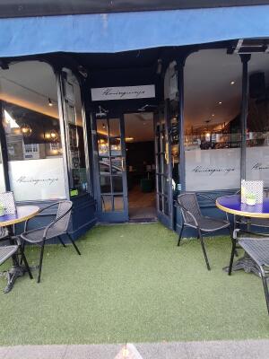 From street, facing venue. Seating on both sides. Grass flooring ahead. Doorway at back.