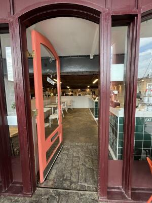 Glass door with orange frame. Metal plate on right. Push to open.