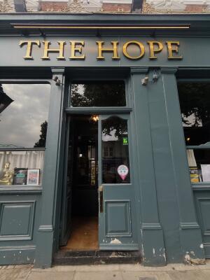 Venue entrance ahead. Blue framed double half glass doors. Push golden bar in centre to open.