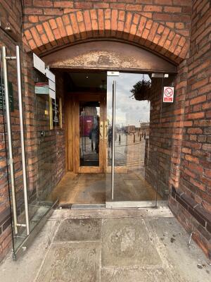 Glass double door with metal handles in centre. Pull to open.