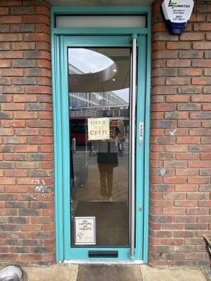 Blue framed glass door. Silver metal long handle on right side of door. Push to open.