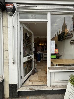 From sidewalk facing venue. White framed glass door ahead. Push door to open.