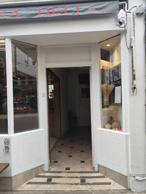 White wood-framed glass door. Pull from handle on left to open. Doorbell for assistance on left frame.