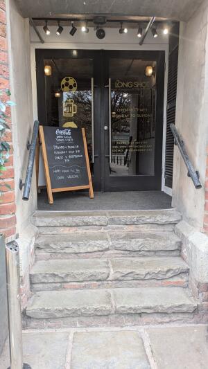 Four steps up to doors followed by doormat. Metal railing on both sides.