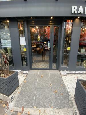 Black framed glass door. Turn and push the black metal handle on right side of door to open.