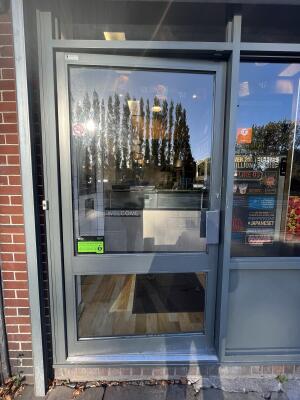 Glass door with grey frame and handle on right. Push to open.