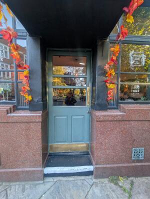 Blue wooden door with glass panels. Gold metal handle on right. Push to open.