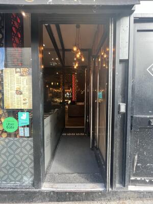 Glass door with a black frame and handle on left. Push to open.