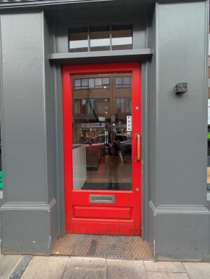 Red frame glass door ahead. Push gold metal handle on right to open.