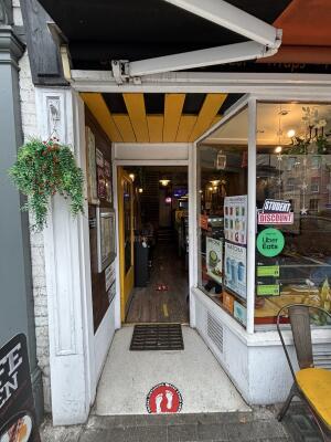 Open archway ahead. Glass door with yellow frame on back. Push from right to open.